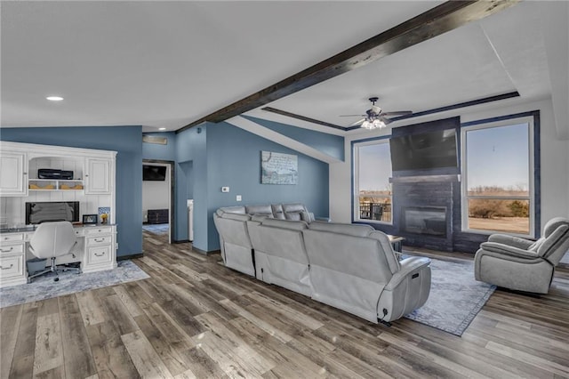 living room with vaulted ceiling with beams, built in study area, wood finished floors, and a ceiling fan