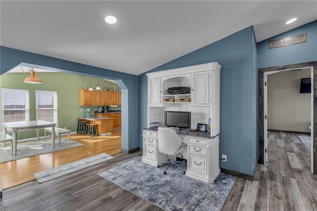 office area with vaulted ceiling, dark wood-type flooring, arched walkways, and baseboards