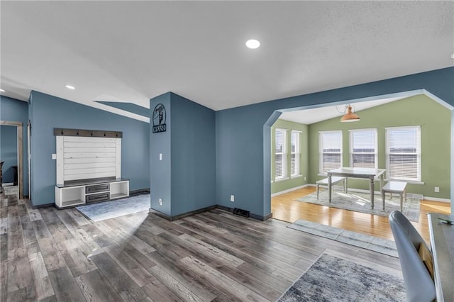 living room featuring arched walkways, lofted ceiling, recessed lighting, wood finished floors, and baseboards