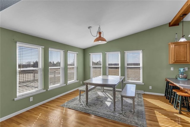 dining area featuring vaulted ceiling with beams, light wood-style floors, and baseboards