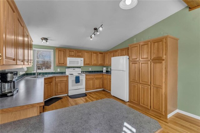 kitchen featuring vaulted ceiling, a sink, light wood-type flooring, white appliances, and baseboards