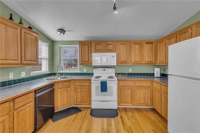 kitchen featuring lofted ceiling, white appliances, light wood finished floors, and a sink