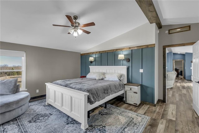 bedroom featuring ceiling fan, lofted ceiling with beams, baseboards, and wood finished floors