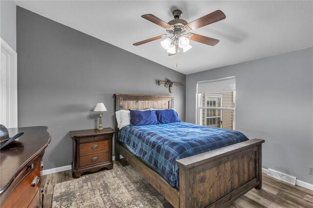 bedroom with visible vents, vaulted ceiling, baseboards, and wood finished floors