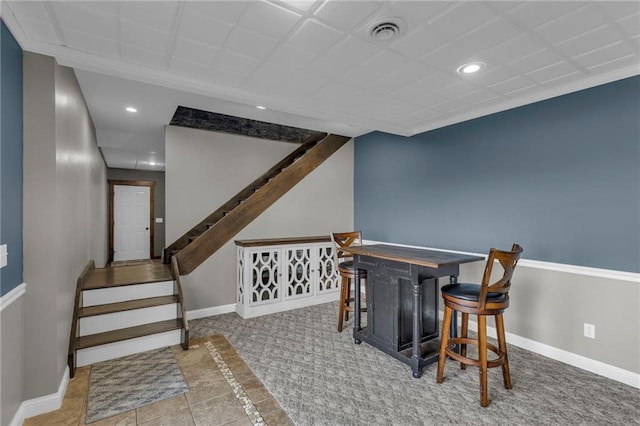 interior space featuring recessed lighting, visible vents, baseboards, stairs, and a bar