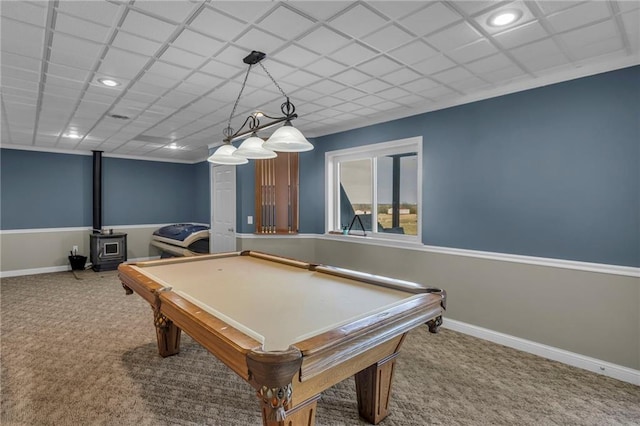 game room featuring a paneled ceiling, carpet, a wood stove, and baseboards