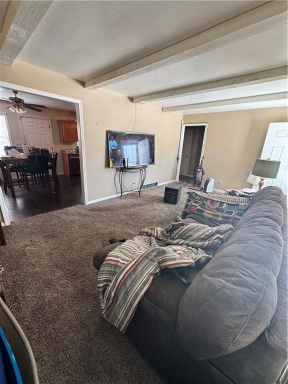 living area with visible vents, dark carpet, a ceiling fan, beamed ceiling, and baseboards