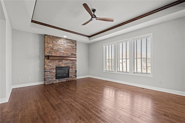 unfurnished living room featuring a tray ceiling, baseboards, dark wood-type flooring, and ceiling fan