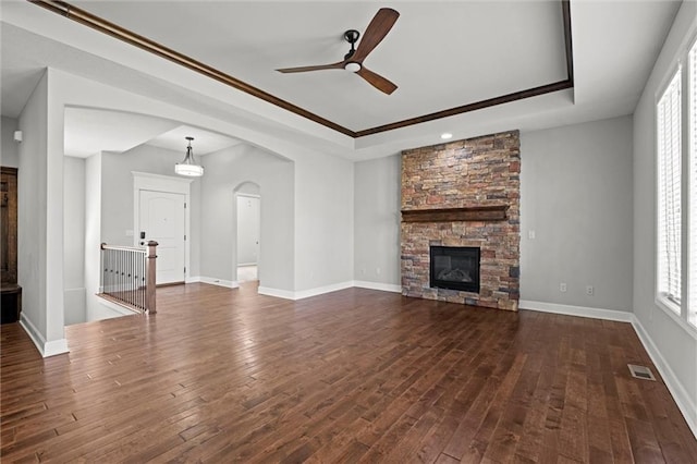 unfurnished living room with visible vents, a ceiling fan, a tray ceiling, baseboards, and dark wood-style flooring