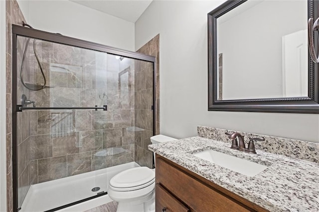 bathroom with vanity, a shower stall, and toilet