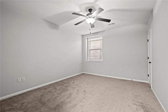 carpeted spare room featuring a ceiling fan, visible vents, and baseboards