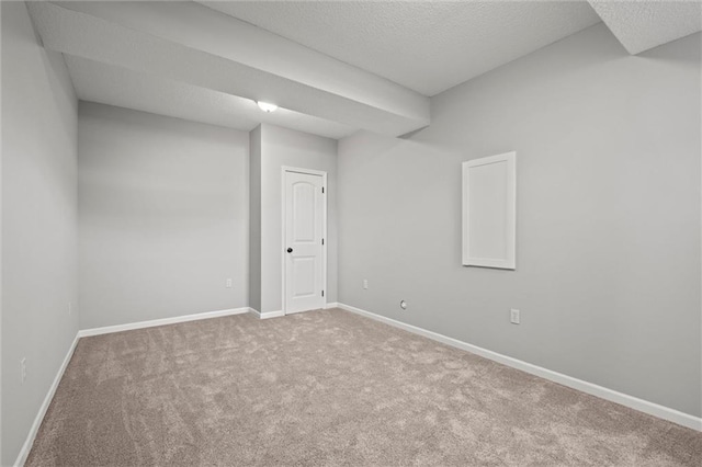 empty room with carpet flooring, baseboards, and a textured ceiling