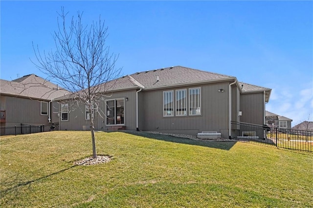 back of property with a lawn, roof with shingles, and fence