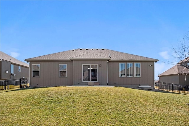 rear view of property featuring a lawn and fence