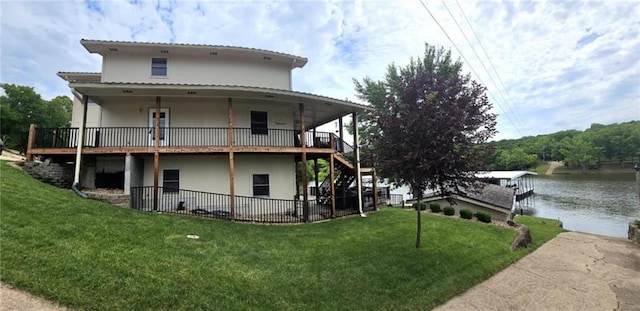 back of house featuring a lawn, a water view, and stucco siding