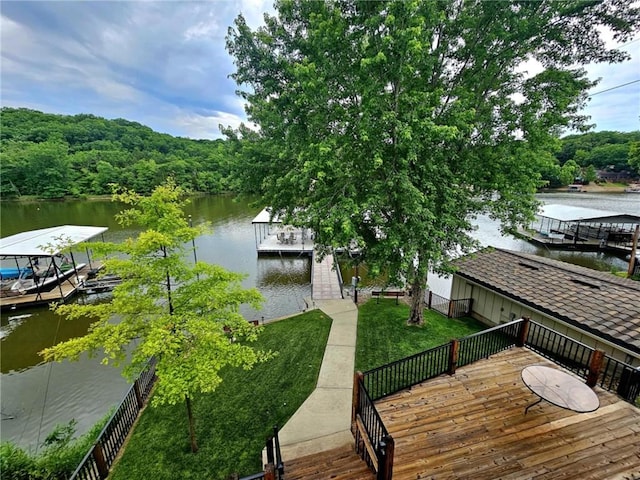 view of dock with a forest view, a lawn, and a water view