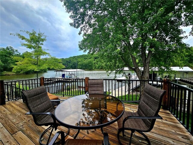 wooden deck with a water view and outdoor dining area