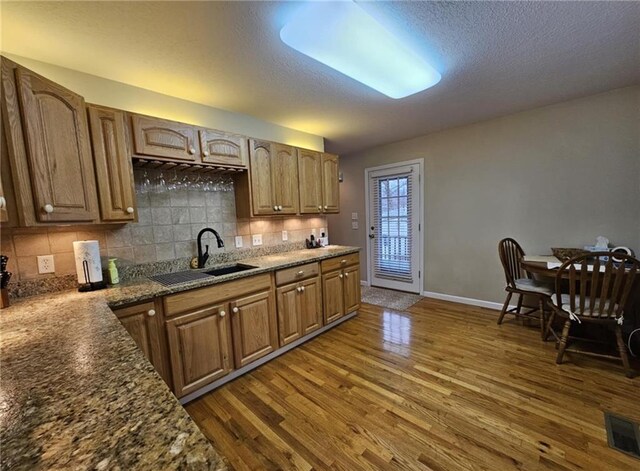 kitchen featuring dark wood-style flooring, brown cabinets, a sink, and visible vents