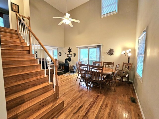 dining space featuring baseboards, visible vents, stairway, wood finished floors, and a wood stove