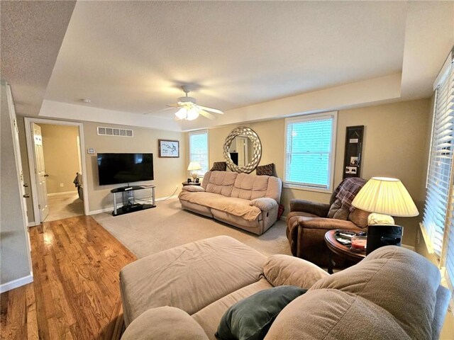 living room featuring a raised ceiling, visible vents, and baseboards