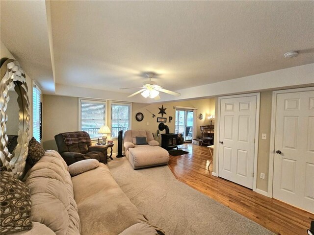 living room with ceiling fan, baseboards, and wood finished floors