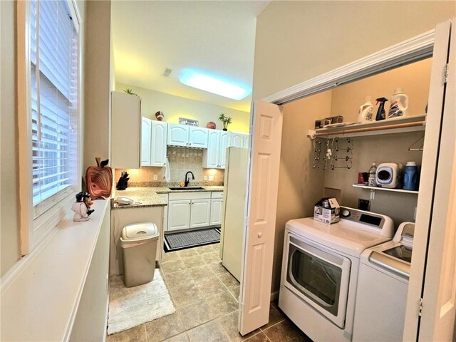 clothes washing area with laundry area, separate washer and dryer, light tile patterned flooring, and a sink