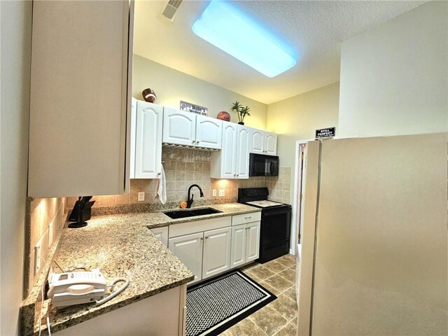 kitchen featuring tasteful backsplash, light stone countertops, black appliances, white cabinetry, and a sink