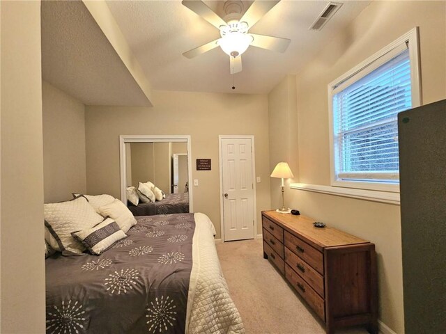 bedroom with baseboards, a ceiling fan, visible vents, and light colored carpet