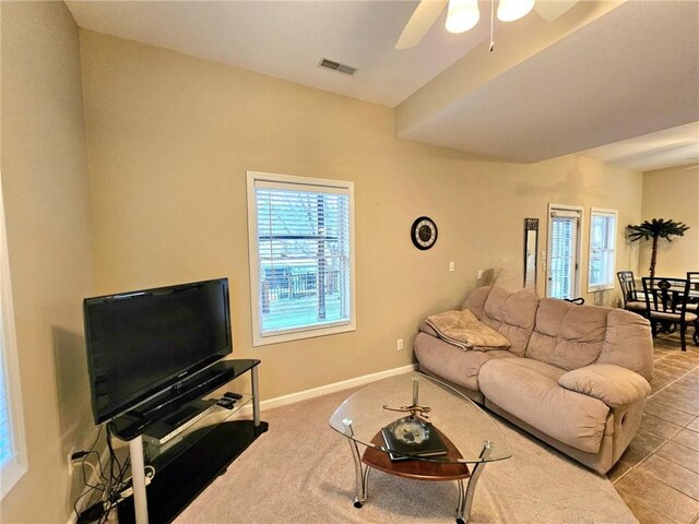 living area featuring visible vents, ceiling fan, light carpet, and baseboards