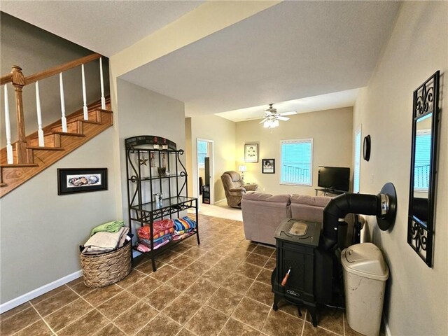 living area featuring stairs, ceiling fan, baseboards, and a healthy amount of sunlight