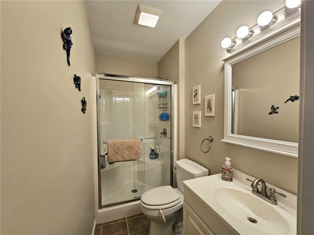 bathroom with tile patterned floors, a shower stall, toilet, and vanity