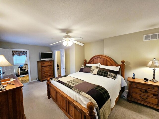 bedroom with baseboards, visible vents, a ceiling fan, light colored carpet, and a textured ceiling