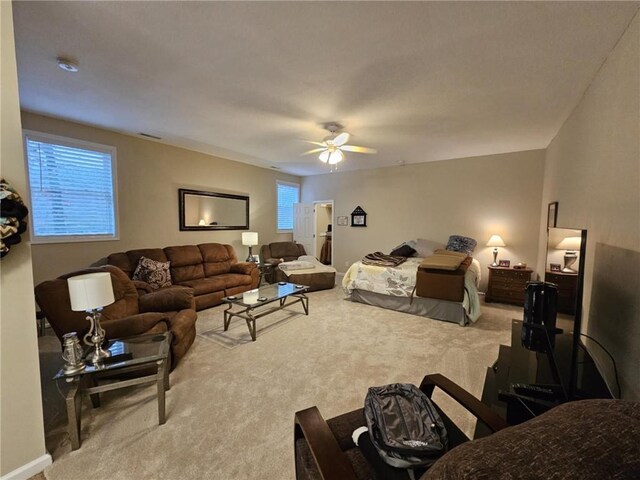 carpeted bedroom featuring visible vents, multiple windows, and a ceiling fan