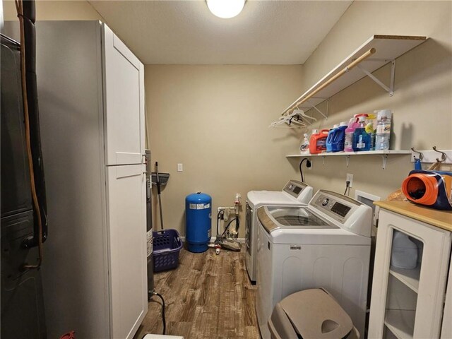 laundry room featuring baseboards, wood finished floors, and washing machine and clothes dryer