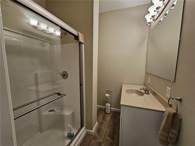 full bath featuring wood finished floors, a shower stall, vanity, and baseboards