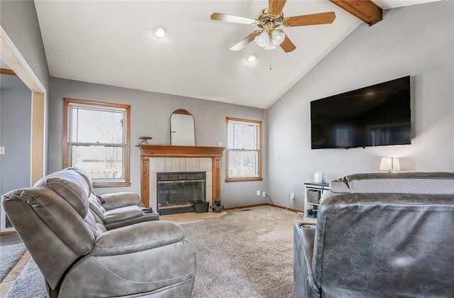 carpeted living area with a tiled fireplace, lofted ceiling with beams, baseboards, and ceiling fan