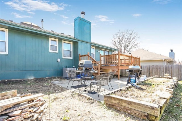 rear view of house with a deck, a patio area, fence, and a chimney