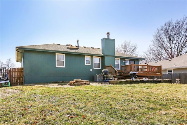 back of property with a deck, a trampoline, fence, and a yard