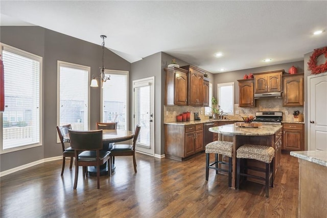 kitchen with stainless steel range, brown cabinetry, a center island, under cabinet range hood, and pendant lighting