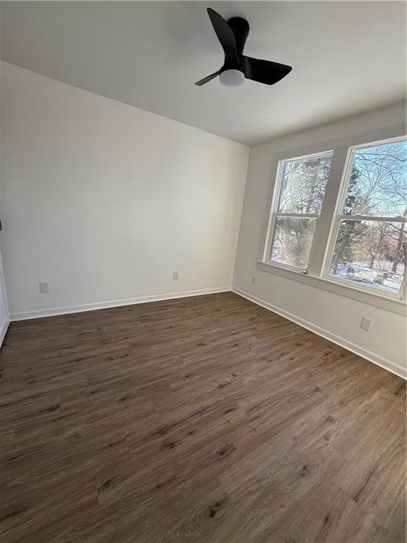 unfurnished room featuring dark wood-type flooring, a healthy amount of sunlight, baseboards, and a ceiling fan