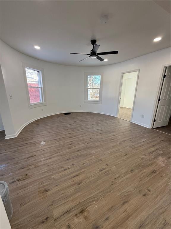 unfurnished living room featuring a wealth of natural light, dark wood finished floors, and recessed lighting