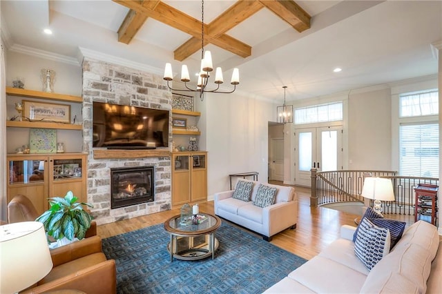 living room featuring light wood-type flooring, a fireplace, beam ceiling, and a notable chandelier