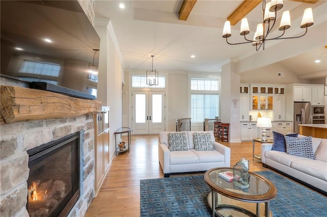 living room featuring french doors, beamed ceiling, a fireplace, and light wood-style flooring