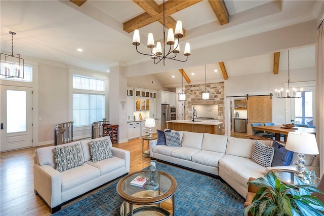 living room with an inviting chandelier, a barn door, and beam ceiling