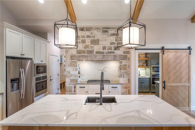 kitchen with an island with sink, light stone countertops, white cabinetry, and stainless steel appliances