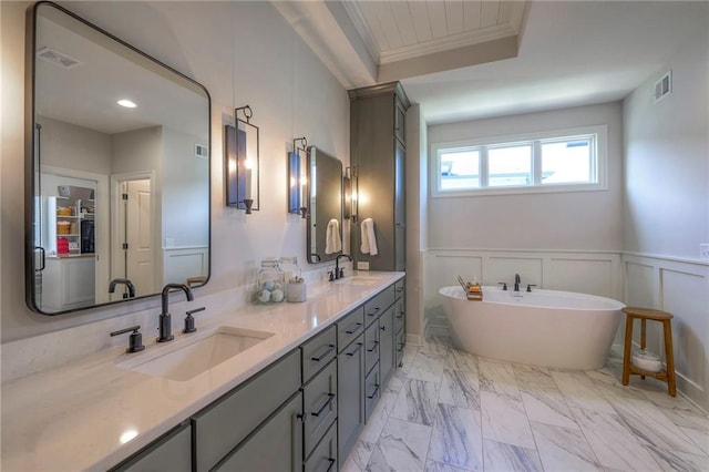 bathroom featuring a freestanding tub, a decorative wall, a sink, marble finish floor, and wainscoting