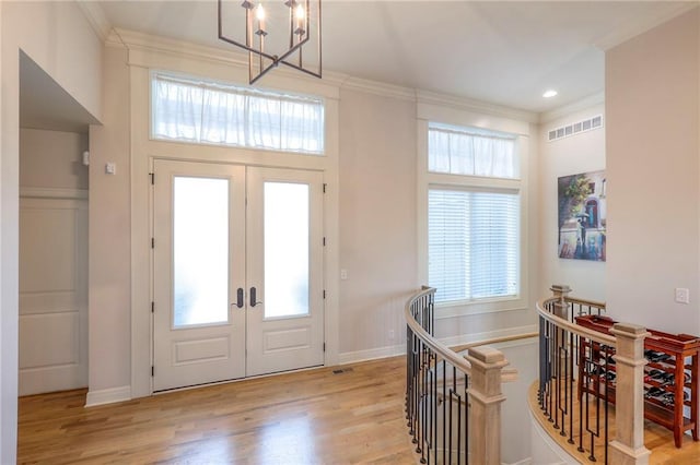 entrance foyer featuring light wood-style floors, plenty of natural light, visible vents, and ornamental molding