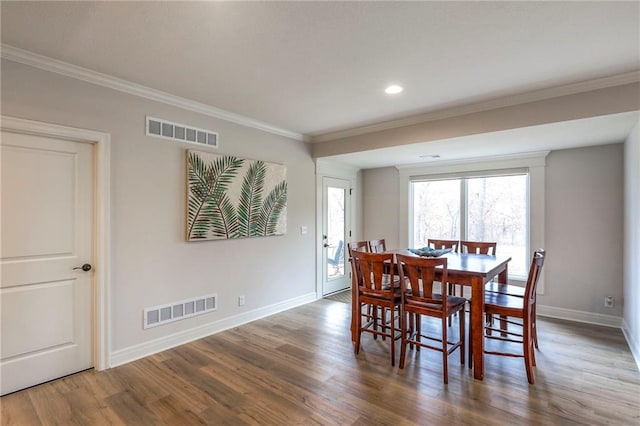 dining room with ornamental molding, wood finished floors, visible vents, and baseboards