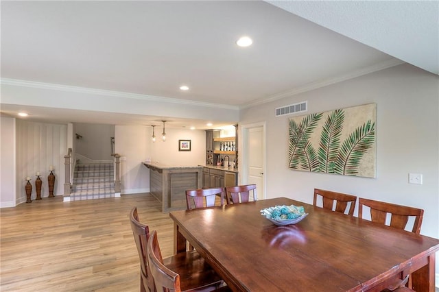 dining area with visible vents, baseboards, stairs, light wood finished floors, and crown molding