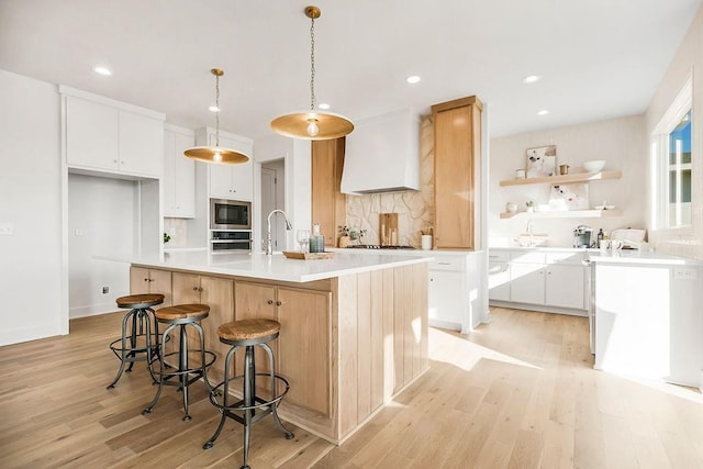kitchen with decorative backsplash, stainless steel appliances, light wood-type flooring, and premium range hood